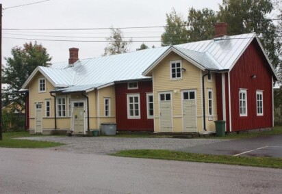 En röd och gul äldre byggnad i två våningar med fyra ingångar.